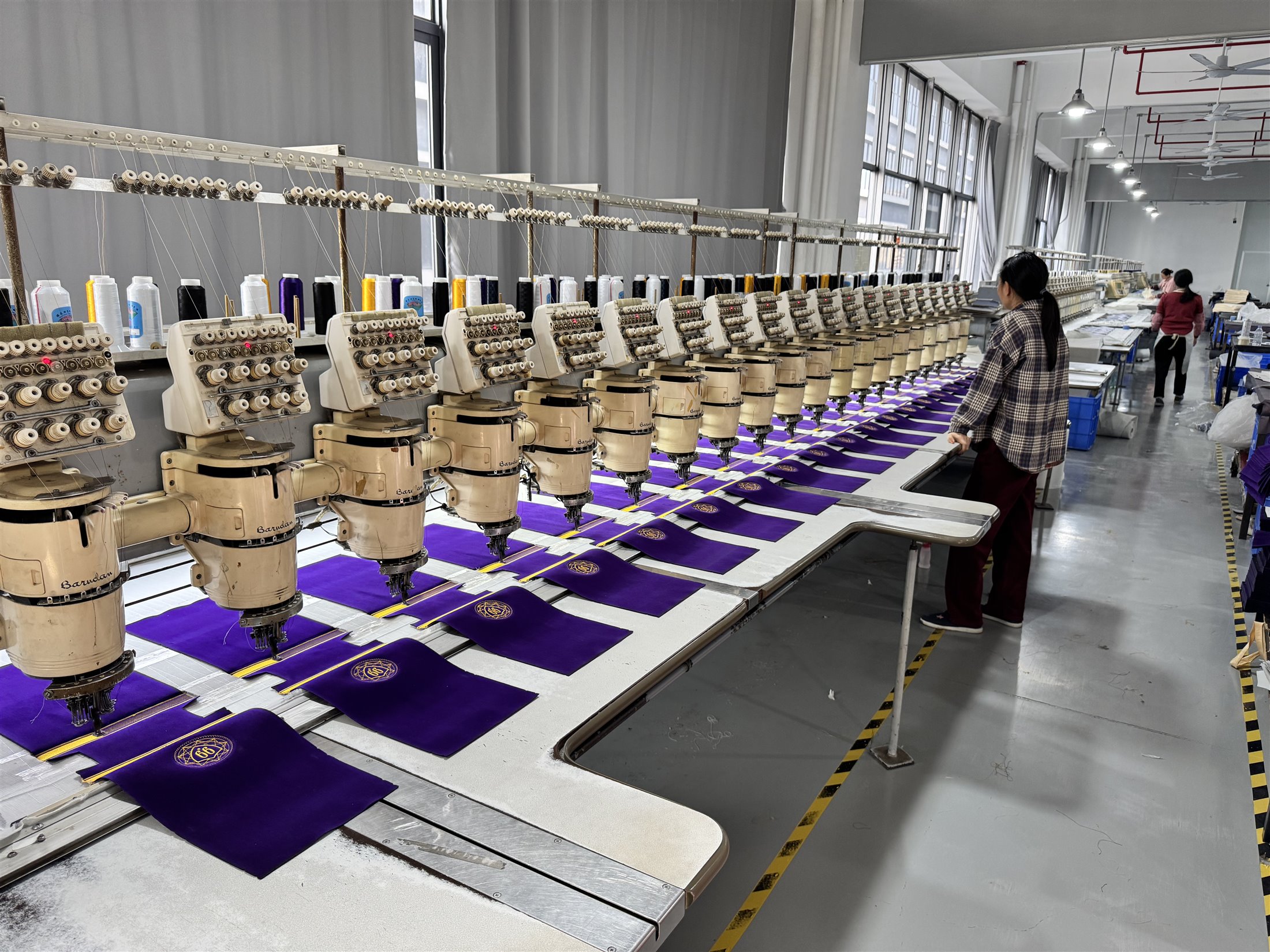 Embroidery machines applying branded details to fabric bags