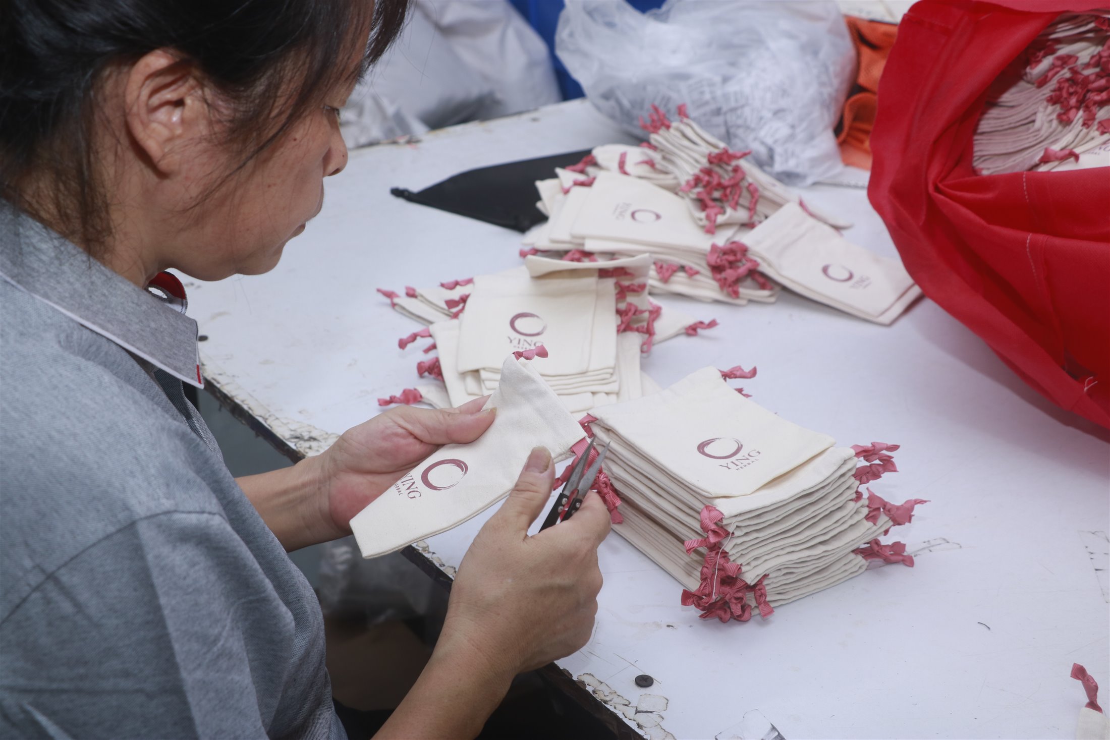 Team member checking the workmanship of finished fabric pouches